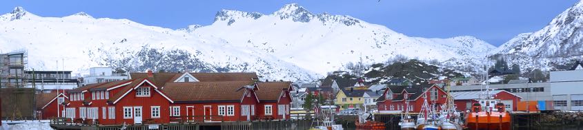Rorbuers (Rorbürs), norwegische Fischerhütten, im Hafen von Svolvaer (Svolvär), dahinter Skitourenberge auf den Lofoten. Foto: Günther Härter.